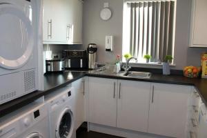 a kitchen with white cabinets and a washer and dryer at The Fountain Inn, Digbeth in Birmingham