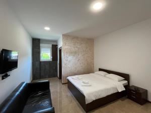 um quarto com uma cama e um sofá de couro preto em Apartmani Bosfor em Niška Banja