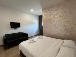 ein Schlafzimmer mit einem Bett und einem Sofa sowie einem Flachbild-TV in der Unterkunft Apartmani Bosfor in Niška Banja
