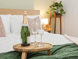 a bottle of champagne and two glasses on a bed at Ty Arth in Llandudno