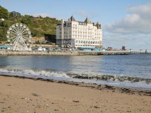 a beach with a building and a ferris wheel at Ty Arth in Llandudno