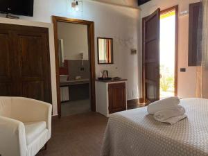 a bedroom with a bed and a chair and a mirror at Tenute Plaia Agriturismo in Scopello