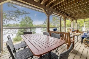 una mesa de madera y sillas en un porche con vistas al agua en Muskoka Lakeshore Cottage Bliss, en Gravenhurst