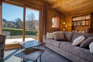 a living room with a couch and a large window at chalet l'Orignal 145m2, 10pers, pied de piste,SPA in Notre-Dame-de-Bellecombe