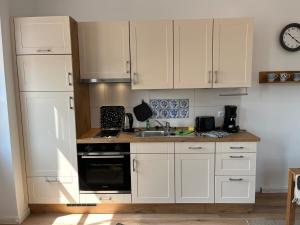 uma cozinha com armários brancos, um lavatório e um fogão em Leevke em Lastrup