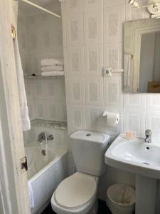 a white bathroom with a toilet and a sink at Malvarrosa Beach Rooms in Valencia