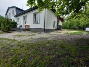 een wit huis met een hond in de voortuin bij Roztoczańskie Apartamenty in Zwierzyniec