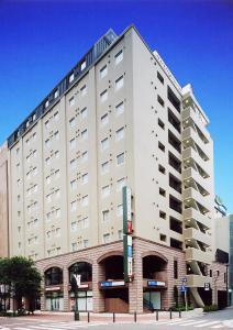 a large white building on the corner of a street at Hotel Route-Inn Yokohama Bashamichi in Yokohama
