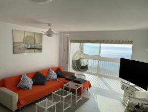 a living room with an orange couch and a balcony at Manhattan apartment in Empuriabrava
