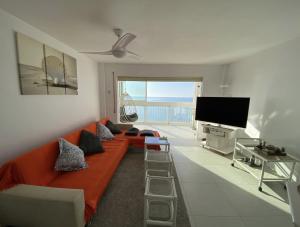 een woonkamer met een oranje bank en een flatscreen-tv bij Manhattan apartment in Empuriabrava