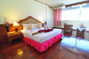 a bedroom with a large bed with a pink skirt on it at Top North Hotel in Chiang Mai