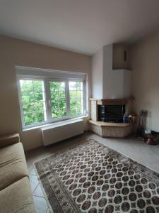 a living room with a couch and two windows and a rug at EverGreen in Kavala