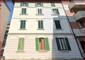 Un edificio alto y blanco con ventanas con contraventanas verdes. en Ciprian, en Bolonia
