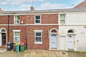 uma casa de tijolos com portas brancas e um parquímetro em St Pauls Square Holiday Home - Preston em Preston