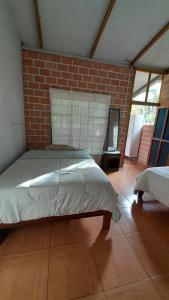 1 dormitorio con 1 cama en una pared de ladrillo en CHOCLINO ECOLODGE -Bungalows en Tarapoto