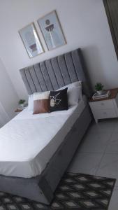 a bedroom with a large bed with a gray headboard at C.leslie_homes in Bamburi