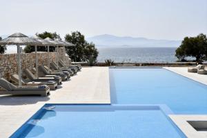 a swimming pool with lounge chairs and the ocean at Ambelas Mare Apartments in Ambelas