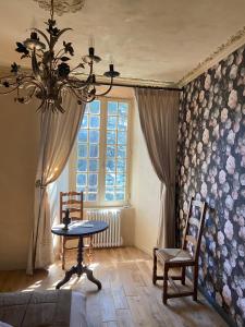 een woonkamer met een tafel en een kroonluchter bij Le Château de Cambiaire in Saint-Étienne-Vallée-Française