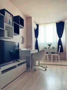 ein Wohnzimmer mit einem Schreibtisch, einem TV und einem Tisch in der Unterkunft Cozy Studio in Cluj-Napoca in Cluj-Napoca