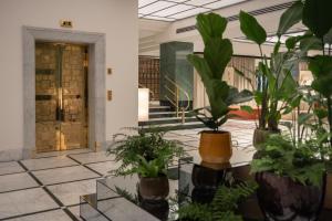 a lobby with a bunch of plants in pots at Almanac X Alcron Prague in Prague