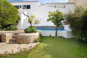 ein weißes Haus mit einem Garten mit Bäumen davor in der Unterkunft Casa da Peixa in Estói