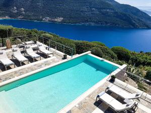 a swimming pool with chairs and a view of a lake at Sundance - Fabulous & Large 4-Bedroom Private Villa in Sivota