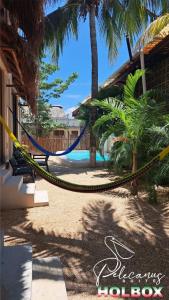 a hammock tied to a house with palm trees at Hotel Pelecanus Suites Holbox in Holbox Island