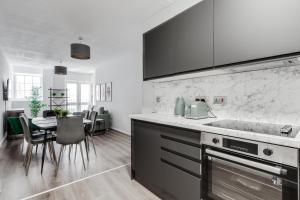 a kitchen with a counter and a table with chairs at Stanley St Suites By GuestFirst in Liverpool