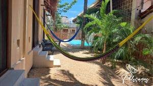 a hammock hanging outside of a house with a pool at Hotel Pelecanus Suites Holbox in Holbox Island