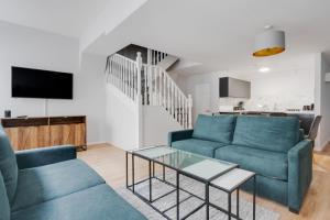 a living room with two blue couches and a table at Stanley St Suites By GuestFirst in Liverpool