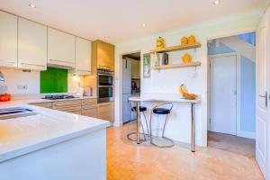 a kitchen with white cabinets and a counter with stools at Beautiful house in Thorpe Bay in Southend-on-Sea