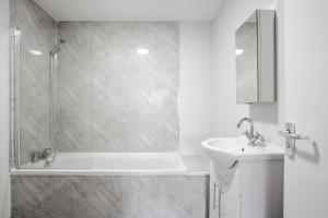a white bathroom with a shower and a sink at Stanley St Suites By GuestFirst in Liverpool
