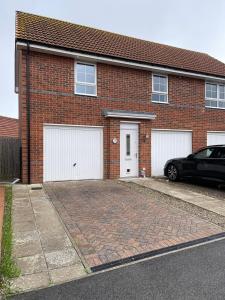 a brick house with two white garage doors and a car at Anox serviced Apartments 2 in Newcastle upon Tyne