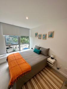 Un dormitorio con una cama grande con una manta naranja. en Novíssimo Apartamento à Beira-Mar en Río de Janeiro