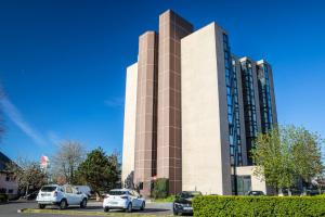 a tall building with cars parked in a parking lot at ibis Paris Creteil in Créteil