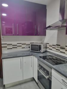 uma cozinha com armários roxos e um micro-ondas em Habitación2 piso lavanda em Vilhena