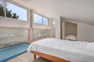 Schlafzimmer mit einem Bett und großen Fenstern in der Unterkunft Maison a trois cent metres de la plage in Saint-Nazaire