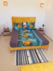 um quarto com uma cama com almofadas azuis e amarelas em DAR ALMATY em Houmt Souk