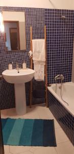uma casa de banho em azulejos azuis com um lavatório e uma banheira em Sines Ocean View Apartment em Sines