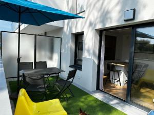 een patio met een tafel en stoelen en een parasol bij Arradon Golfe du Morbihan Appartement 2 Pièces plain-pied Terrasse in Arradon