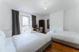 a white bedroom with two beds and a window at Holloway Road Double rooms - 5 in London