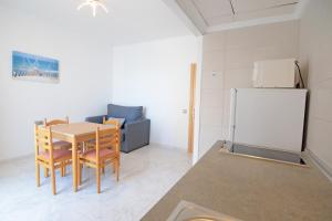 uma cozinha com uma mesa e cadeiras e um frigorífico em Apartamentos Playa Sol em Es Cana