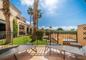 a patio with two benches and a fence with palm trees at Casa de la vida - Roda Golf in Roda