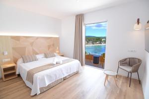 a bedroom with a bed and a view of the ocean at Apartamentos Playa Sol in Es Cana +63 photos