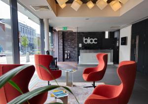 a lobby with red chairs and a living room at Bloc Hotel Birmingham in Birmingham
