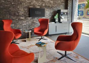 a lobby with three chairs and a tv on a brick wall at Bloc Hotel Birmingham in Birmingham