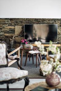 a living room with tables and chairs and a stone wall at Casa do Santo - Wine & Tourism in Provesende