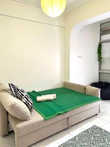 uma sala de estar com um sofá e um cobertor verde em Charming House 2 na Amadora