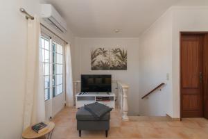 een woonkamer met een flatscreen-tv en een bank bij Casa Oceanus - 2BDR House w Pool & Balcony in Cabanas de Tavira