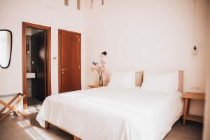 a white bed with white sheets and pillows at MAZI - Pied à Terre in Rethymno Town